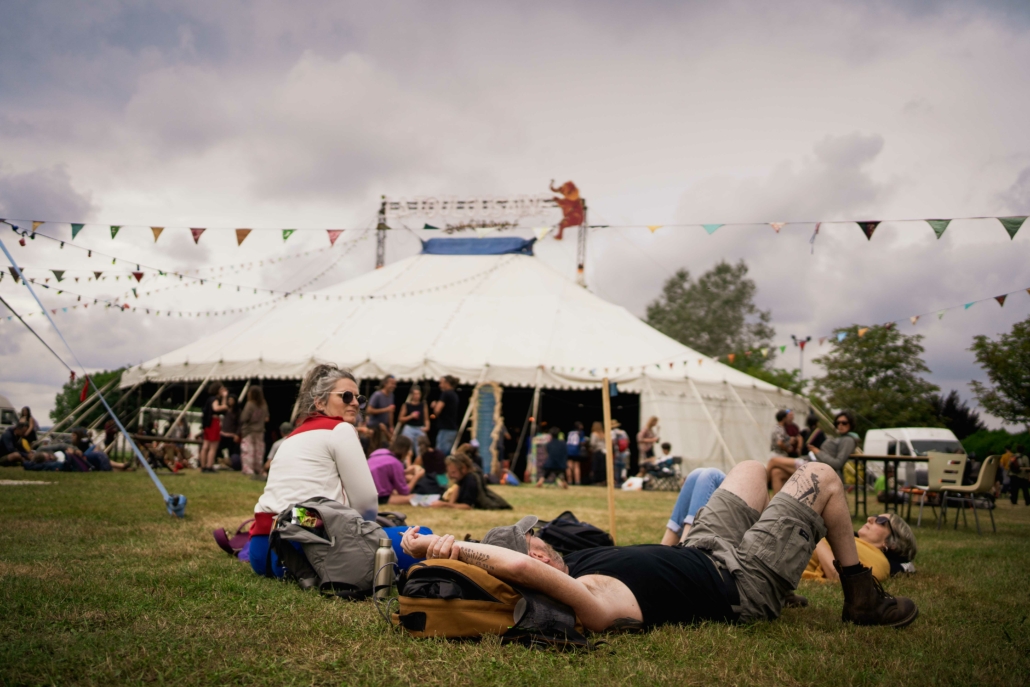 Devant un chapiteau de cirque, un homme et une femme se reposent